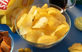 A bowl of chips and other snacks on a blue table.