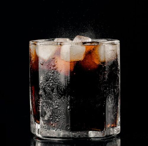 Short glass of dark diet soda with ice.